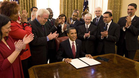 obama sit at desk with staff