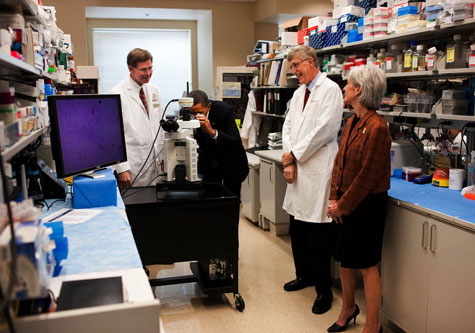 Obama looking at a microscope